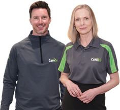 two people standing next to each other in front of a white background wearing grey and green shirts