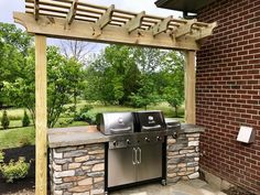 an outdoor bbq with grill and pergolated area