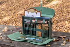 a wooden table topped with an open case filled with pens and pencils