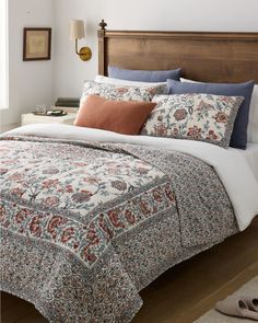 a bed with an orange and blue comforter on it