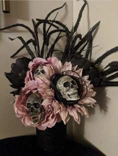 a vase filled with flowers and skulls sitting on top of a black table next to a wall