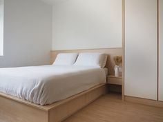 a white bed sitting on top of a wooden platform next to a window in a bedroom