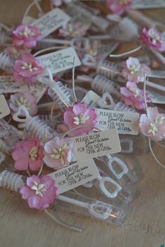 some pink flowers and tags are on a clear plastic container with string attached to it