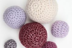 four crocheted balls sitting next to each other on top of a white surface