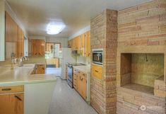 a kitchen with wood cabinets and an oven in the center, along with a brick wall