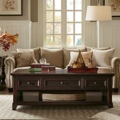 a living room with couches, coffee table and lamps on the windowsills