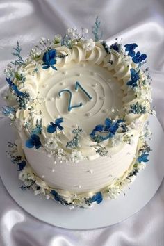 there is a white cake with blue flowers on it and the number twenty seven in the middle