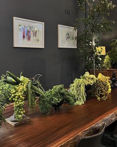 a table topped with lots of green vegetables on top of a wooden table next to pictures