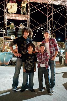 three young men standing next to each other in front of scaffoldings at night