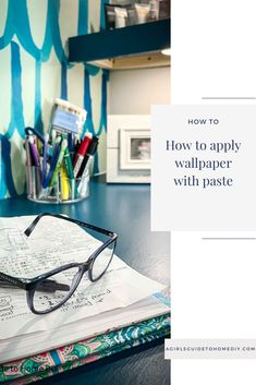 a pair of glasses sitting on top of a book next to some pens and pencils