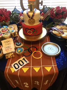 a table topped with a cake covered in olympic rings and medals on top of it