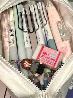 a white bag filled with lots of different types of pens and pencils on top of a table