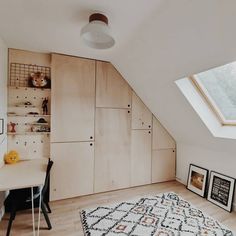 an attic bedroom with white walls and wooden floors, built - in shelving units