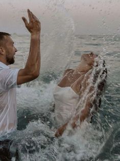 a man and woman in the water with their hands up to each other as they float