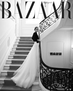 a woman in a long white dress is standing on the stairs next to a staircase