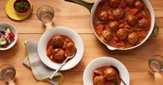 two bowls filled with meatballs and veggies on top of a wooden table