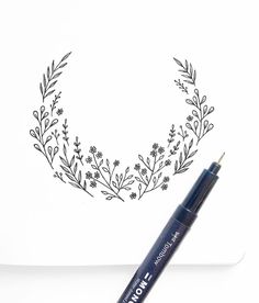 a pen is sitting on top of a piece of paper next to a drawing of a wreath