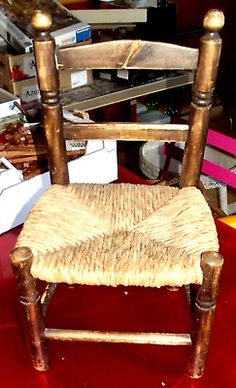 a wooden chair sitting on top of a red table next to boxes and other items