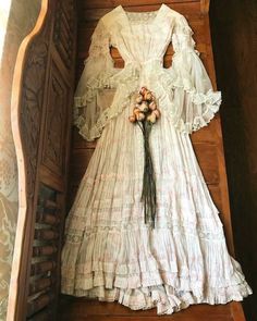 an antique dress is displayed in a wooden box with flowers on the bottom and inside