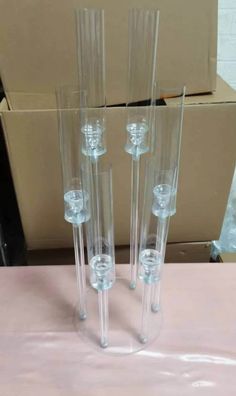 three tall clear glass vases sitting on top of a pink tablecloth covered table