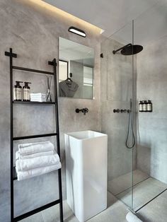 a bathroom with a stand up shower and white towels on the shelf next to it