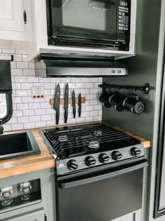 a stove top oven sitting inside of a kitchen next to a microwave above a counter