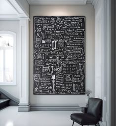 a black and white chalkboard hanging on the wall next to a chair in a room