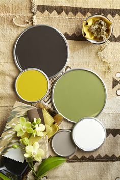 four different shades of paint sitting next to each other on top of a table with flowers