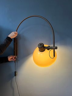 a person is lighting a yellow light on the wall with a lamp attached to it