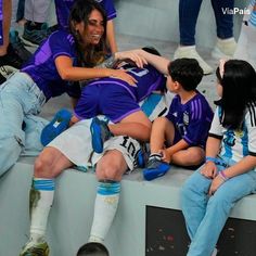 a group of people sitting on top of a bench next to each other at a soccer game