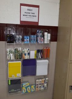 there is a shelf with many items on it in the bathroom stall, and one has a sign that says free toilet care what - you need