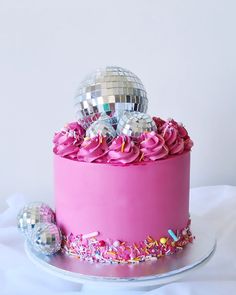 a pink cake with two disco balls on top and sprinkles around it