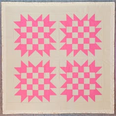 two pink and white quilts are on the ground with one block in the middle