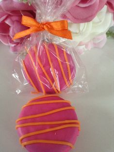 two heart shaped cookies wrapped in cellophane with orange and pink stripes on them