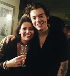 a man and woman are posing for a photo with their arms around each other while holding wine glasses