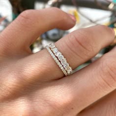 a woman's hand with three diamond rings on top of her finger and the bottom half of her wedding band