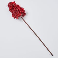 a red flower on top of a wooden stick