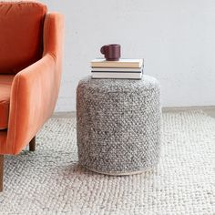 an orange chair sitting next to a stack of books on top of a white rug