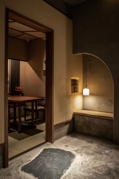 an empty room with a table and chair in it, lit by a light on the wall