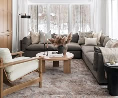 a living room filled with lots of furniture next to a large window covered in white curtains