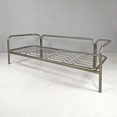 a metal bed frame sitting on top of a white floor next to a gray wall