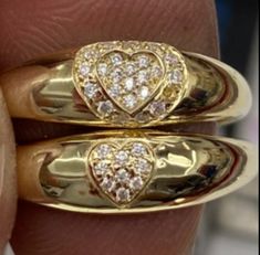 two gold rings with diamonds in the shape of hearts on each one's fingers