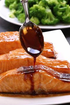 salmon being drizzled with brown sauce on top of it and broccoli in the background