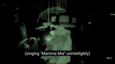 a person laying on a bed in a dark room with the words singin'mama mia'unintelibly