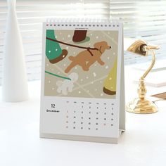 a calendar sitting on top of a desk next to a lamp