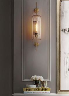 a white table topped with a vase filled with flowers next to a wall mounted light