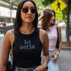 two women are walking down the street wearing sunglasses and one is looking off to the side