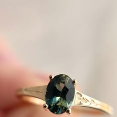 a close up of a person holding a ring with a green stone in the middle