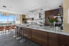 a kitchen with marble counter tops and bar stools in front of a large window