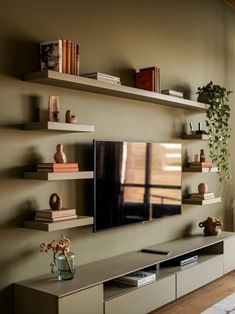 a flat screen tv sitting on top of a wooden shelf next to a wall mounted television